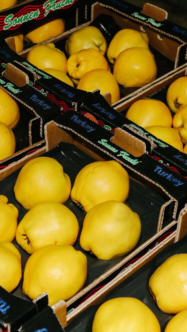 Numerous yellow, fresh fruits lie next to each other in cardboard boxes.