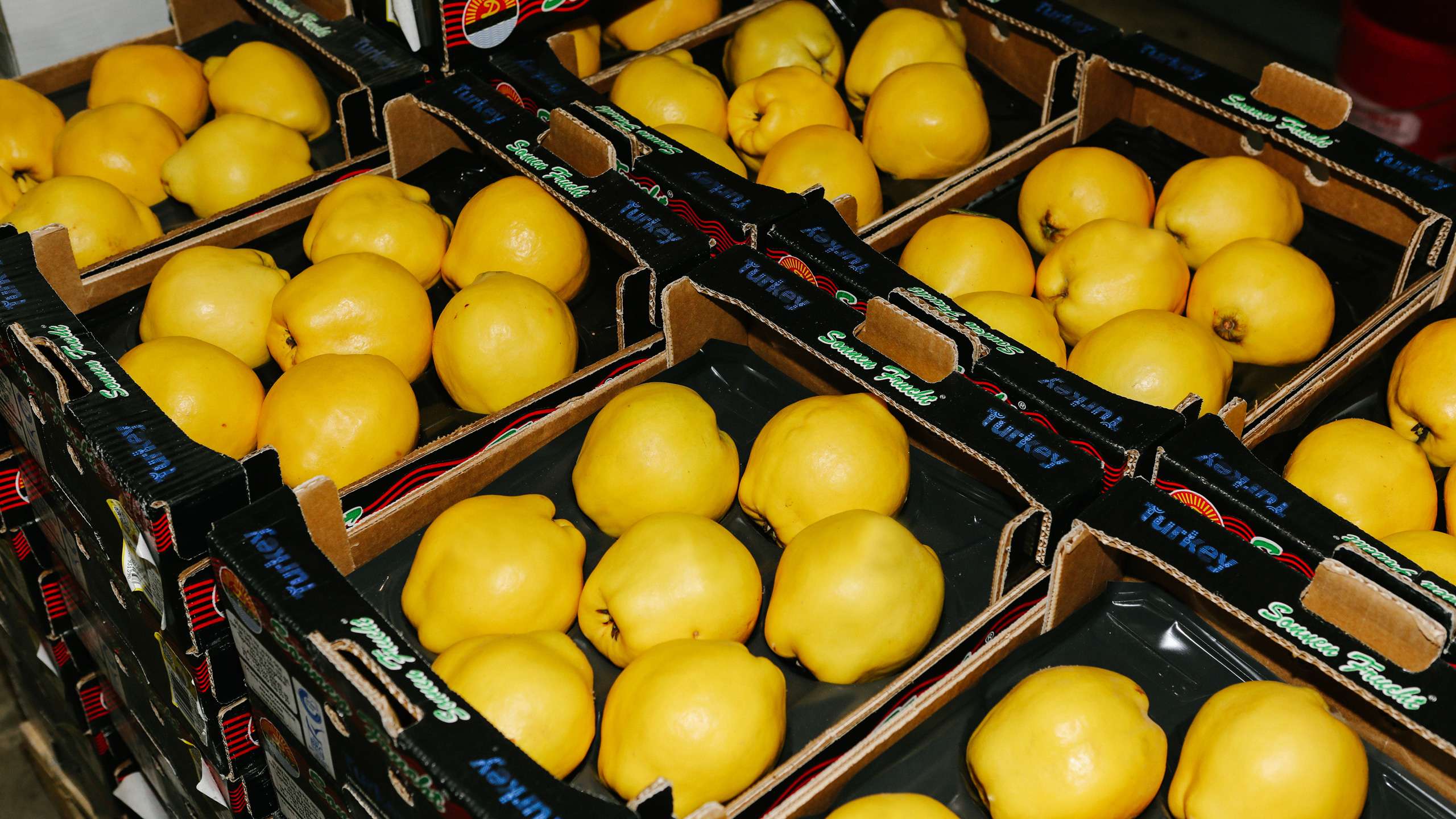 Numerous yellow, fresh fruits lie next to each other in cardboard boxes.
